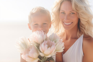 Obraz na płótnie Canvas Beautiful blonde mother and child holding pink flowers on sunny summer day. Summer fun for family with kids outdoor.