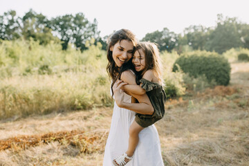 Happy moment of mother playing with her daughter outdoors in a park on a summer day, laughing....