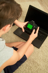a boy with a camera next to a laptop computer