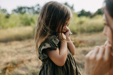 Little sad girl crying while her mother is comforting her, outdoors, in a park.
