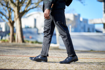 Cropped image of businessman feet walking, with cityscape background. 