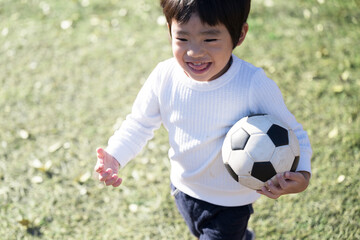芝生でサッカーをする楽しそうな男の子 © kapinon
