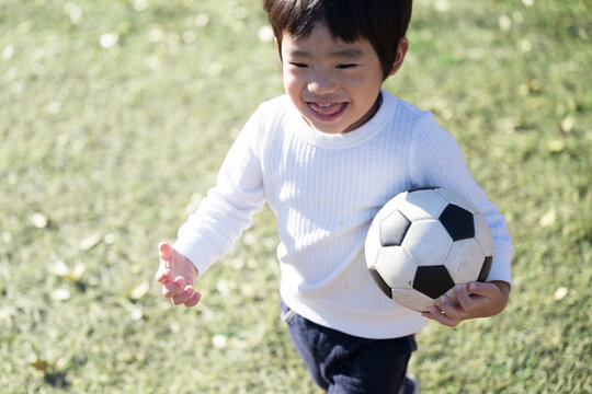 芝生でサッカーをする楽しそうな男の子