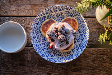 Syrnik with frozen blackberries, blueberries and cream on a wooden background.
cheese pancake. 