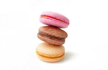 Three colored French macarons stacked on top of each other in a tower on a white background with space for text. Macaroons cakes of different colors. Culinary and cooking concept.