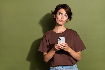 Photo portrait of attractive young woman gadget look skeptical empty space dressed stylish brown...