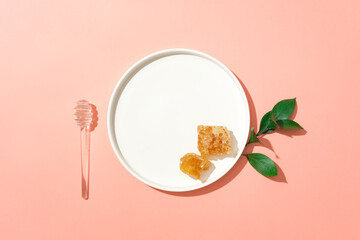 Top view of a ceramic dish with beeswax placed on, decorated with a honey dripping and some leaves. Honey is a natural antiseptic and anti-inflammatory