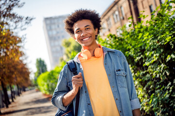 Photo of positive good mood guy dressed jeans shirt headphones walking college outdoors urban city park