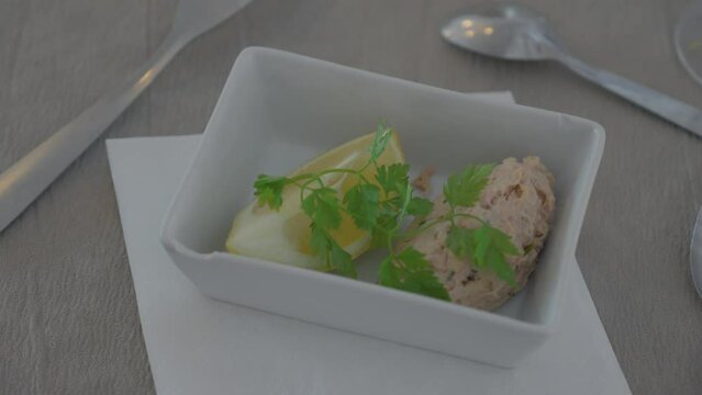 Small plate with french petit apetizer, peace of lemon with koriander and tuna.