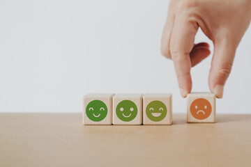 smiling face on wooden cube block  with blurred hand move out bad emoticon, for customer feedback, satisfaction survey ,mental health assessment, child wellness, world mental health day