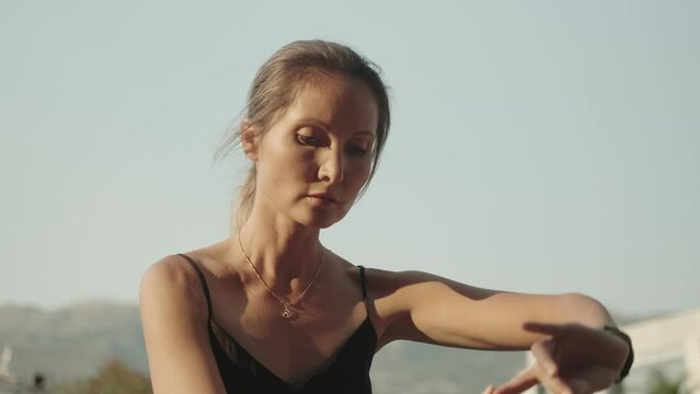 A beautiful young woman moves smoothly against the sky while practicing qigong. Solitude, harmony, meditation. The instructor of oriental practices is engaged in solitude and practices.