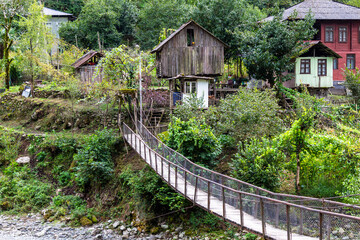 travel to Georgia - suspension bridge with wood flooring in Scurdidi village over Scurdidi river in Adjara on autumn day