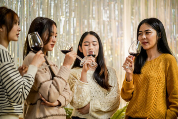 Cheerful friends enjoying home Birthday holiday party. Asian Friends cheering drinking red wine celebrating New Year party.