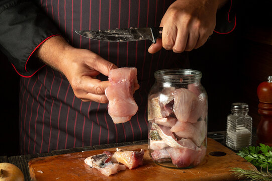 The chef prepares fresh carp fish. The cook's hand puts a fish steak into a jar for pickling. Working environment in a restaurant kitchen