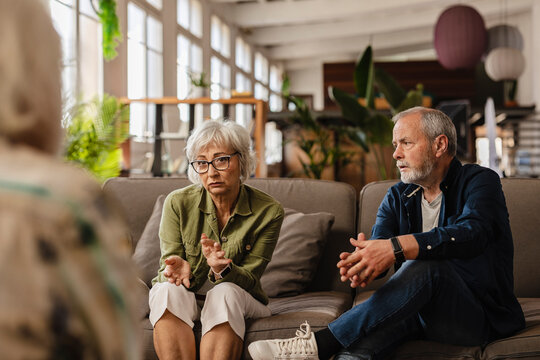 senior couple therapy. Woman arguing with her therapist while husband listens attentively to the couple's relationship problems in front of his psychologist - mental health concept