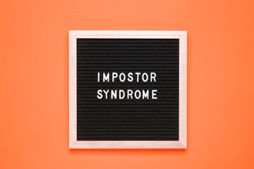 The word Impostor Syndrome, Mental Health quotes on black letter board over isolated orange...