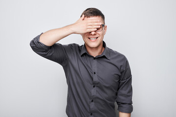 Portrait of young businessman covering eyes with hand isolated on white studio background.