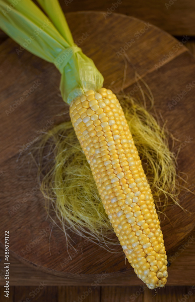 Poster corn cob. Fresh corn on the cob on a rustic wooden table, close up