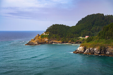 Fototapeta premium Heceta Head Lighthouse on the Pacific Coast amidst rugged mountains, overlooking the expansive Pacific Ocean near Florence, Oregon. A popular landmark and tourist attraction.