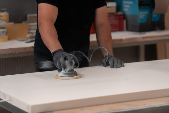 A skilled craftsman in the woodworking industry meticulously operates a wood polishing machine, showcasing his expertise and dedication to achieving a flawless finish in the production of finely