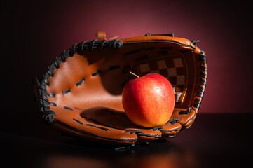 a baseball glove and an apple. Concept of healthy food and lifestyle