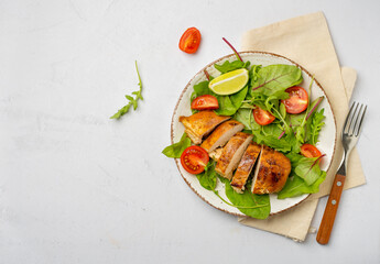 Salad with chicken breast, fillet with lettuce and cherry tomatoes on a plate on a light background, horizontal, free space for copying..