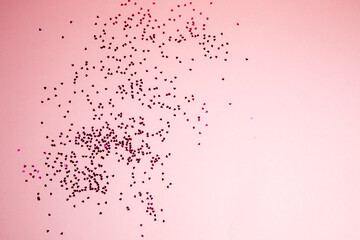 Greeting background with empty space. Violet sparkle sequins, glitter in heart shape on a gentle pink background. Top view
