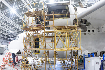 Close-up white transport aircraft in the aviation hangar. Airplane under maintenance. Checking...