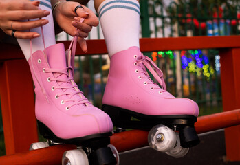 Close-up of figure skater's hands tying shoelaces on roller skates, young woman roller skating in the park close-up - obrazy, fototapety, plakaty