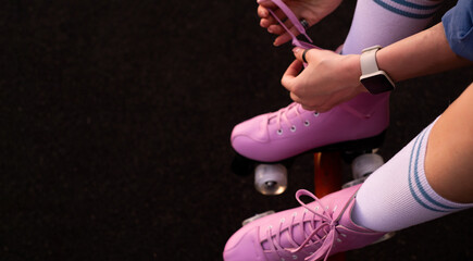Close-up of figure skater's hands tying shoelaces on roller skates, young woman roller skating in...