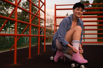 Close-up of figure skater's hands tying shoelaces on roller skates, young woman roller skating in...