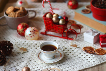 Various colorful Christmas decorations, soft blanket, cup of tea, sweet snacks and lit candles on the table. Cozy Christmas atmosphere at home. Selective focus.