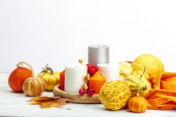 Autumn cozy composition. Pumpkins in a basket, candles, cones, seeds. Traditional fall decor