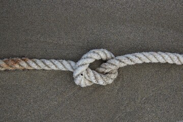 evocative image of a rope with a knot on the sand
of a beach in Italy