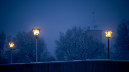 Street lamps on the stone bridge in Regensburg at night in winter with snow