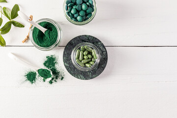 Three glass jars with organic green algae spirulina product in tablets, capsules, powder. An alternative to medicine. Top view. white background.