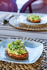 a pair of slices of toast topped with grated tomatoes and smashed avocado at a restaurant.