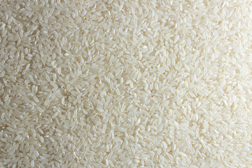 Dry Uncooked White Rice Background - Top View, Flat Lay. Scattered Raw Long Grain Rice. Asian Cuisine and Culture. Healthy Eating Ingredients. Diet Food