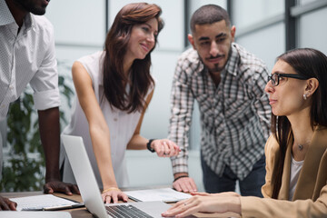 Happy young female worker discussing online project, showing presentation to experienced team leader in glasses.