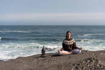 girl meditates in a national Icelandic sweater at sunset 