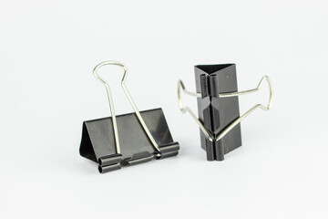 A tool for clamping or holding sheets of paper together. Made from black painted steel sheet.