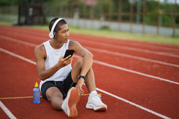 Asian man sportsman fit body wearing white headphone and using mobile phone on white screen to...