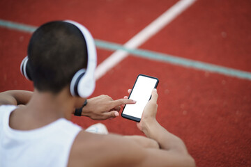 Asian man sportsman fit body wearing white headphone and using mobile phone on white screen to...