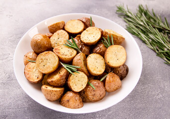 Delicious baked potatoes with rosemary on a gray background