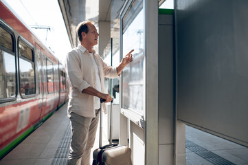 Passenger searching train in timetable on train station in city.
