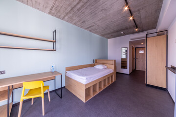 Simple student-style dorm bedroom. Hostel dormitory room. Campus