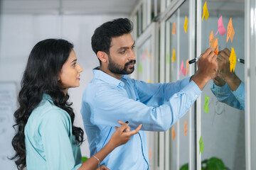 Two colleagues or young businesspeople at office planning or solving corporate problem by...