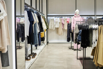 Wide shot of modern clothing store interior with garments for sale hanging on racks