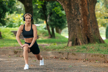 Sporty woman warming up before running and listening music in earphones.