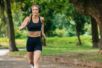 Sporty blonde runner woman running in park.